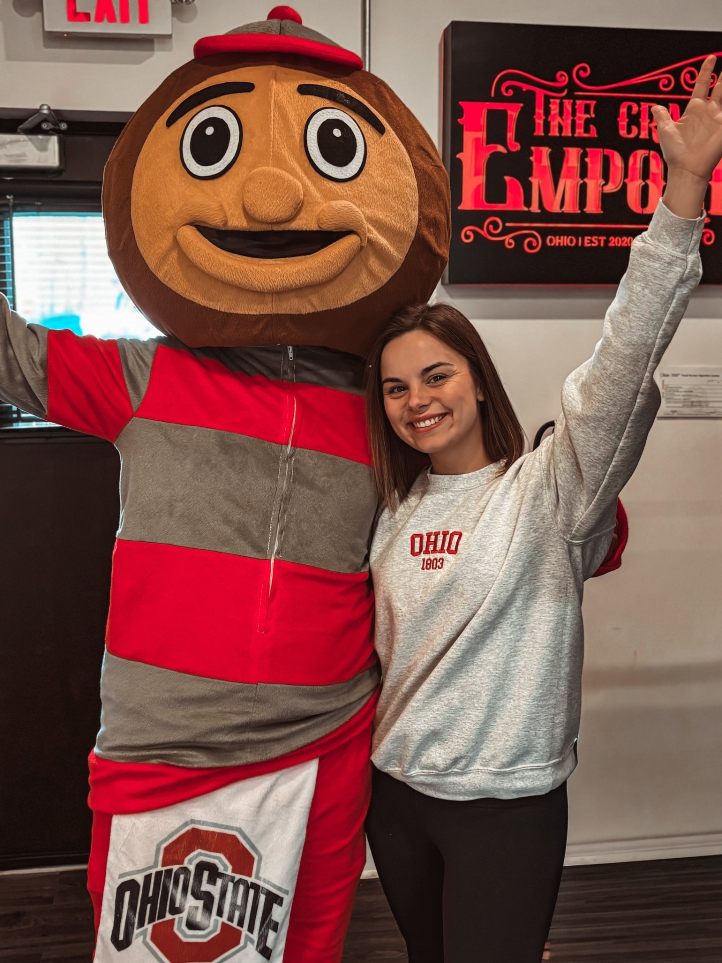 Fan posing with Brutus Buckeye at The Craft Emporium